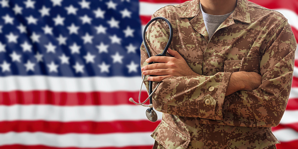 Soldier with stethoscope in an American military uniform, standing on a USA flag background