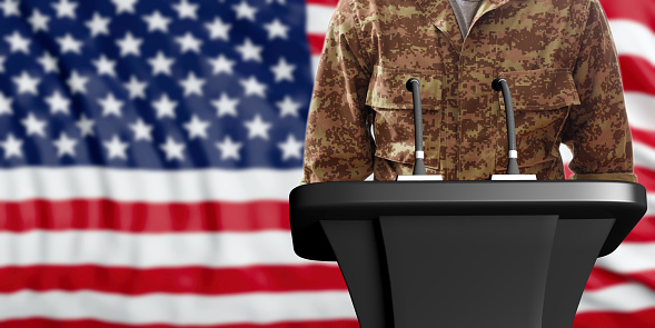 Speaker in an American military digital pattern uniform, standing on a USA flag background. 3d illustration