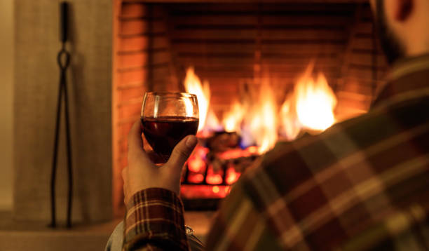 istock Man holding a glass of wine fireplace in front 1008922474