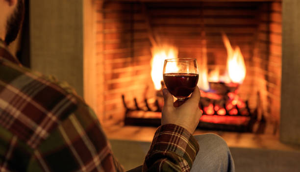 istock Man holding a glass of wine fireplace in front 1008922476