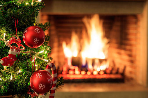 Christmas tree close up on blurred burning fireplace background