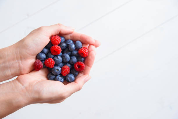 istock Fresh blueberries and raspberries in women's hands 1008923210
