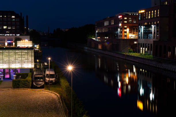 nachtaufnahme von einem hafen am teltow-kanal in berlin-tempelhof mit lagerhallen und reflexionen von bunten lichtern auf dem wasser. - teltow stock-fotos und bilder