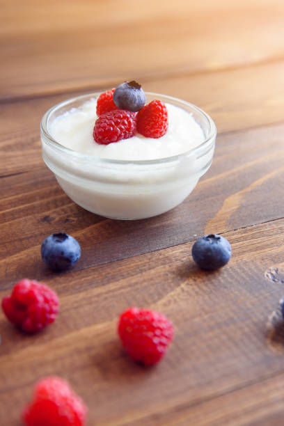 istock Yogurt with fresh blueberries and raspberries on a wooden background. 1008929718