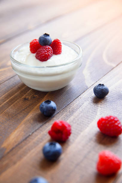 istock Yogurt with fresh blueberries and raspberries on a wooden background. 1008929720
