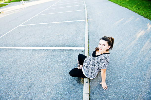 Minimal portrait of pregnant young woman with tattoos posing against grey background and looking at camera, copy space