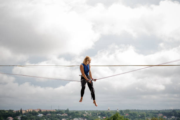 istock Female equilibrist sitting on the slackline rope 1008952570