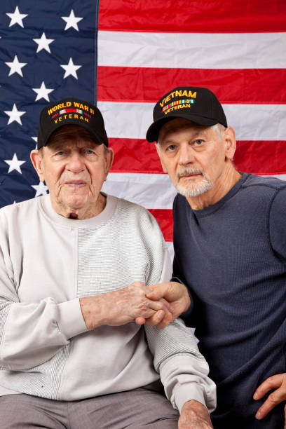 istock World War Two Veteran and Vietnam Veteran shaking hands looking at camera. 1008984954