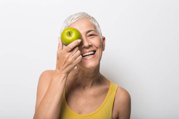 istock Smiling older woman with an apple on her face 1008988078