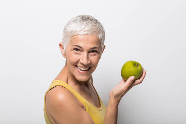 istock Mature woman holding an apple and looking at camera 1008988084