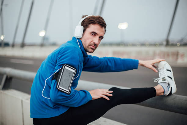 istock Tired young man listening music with headphones while exercising 1009004178