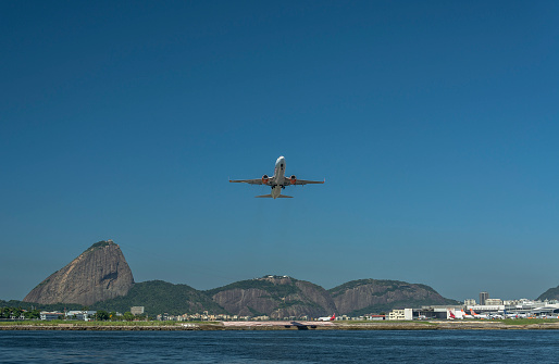 Photo taken from Santos Dumont Airport in Guanabara Bay, view of the sea to the mainland, with the hills of Urca and Sugar Loaf, with a plane taking off