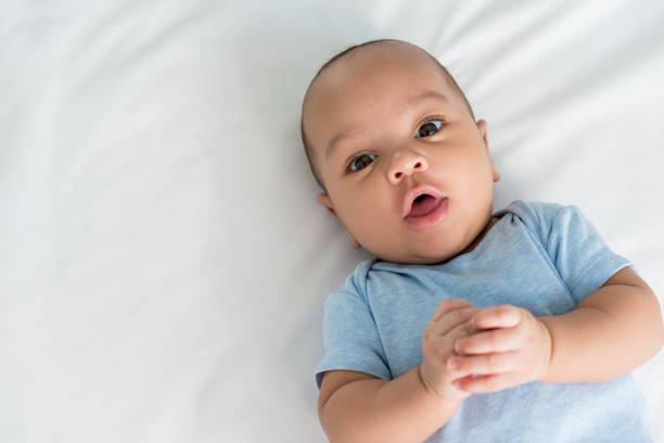 infant little baby with surprised expression looking at camera while lying in bed infant little baby with surprised expression looking at camera while lying in bed cute black babys stock pictures, royalty-free photos & images