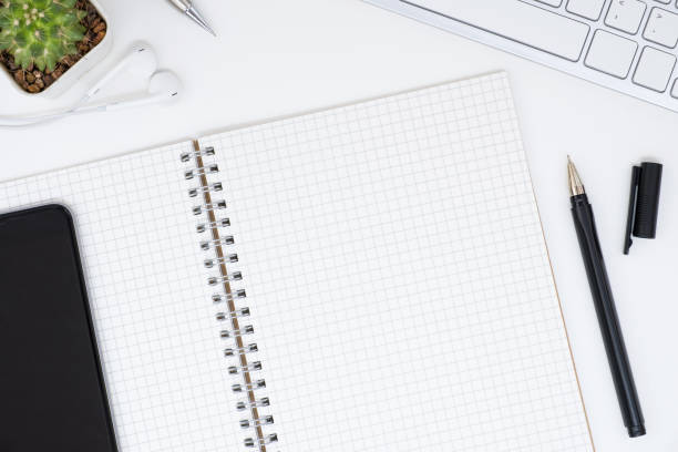 istock Top view of blank grid notebook page on top of white office table, flat lay. 1009020466