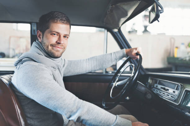 istock Handsome man sitting inside his vintage car 1009024926