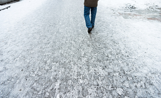 Man walking in the road covering with snow.