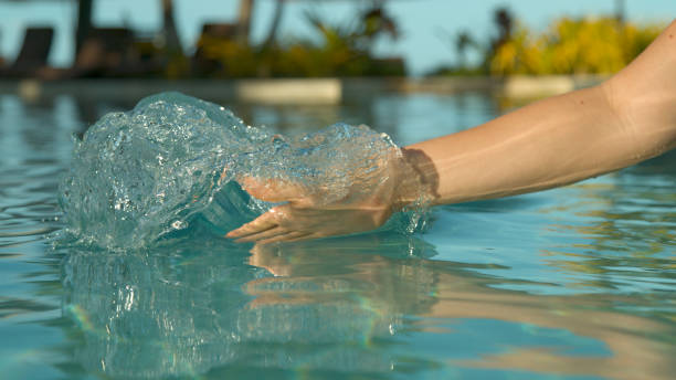 istock CLOSE UP: Playful female tourist drags her hand through water and creates a wave 1009028664