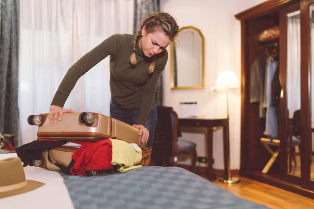 istock Angry woman struggling with overflowing suitcase 1009031074