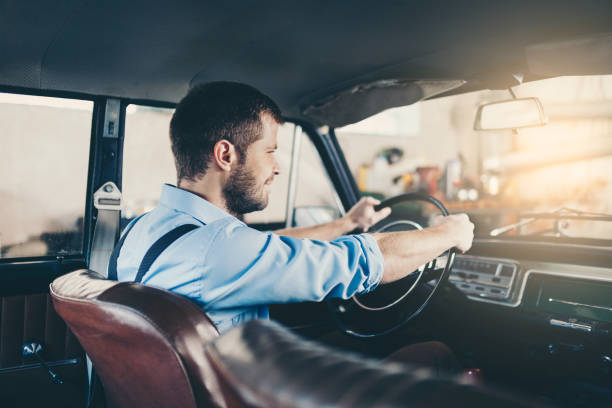 istock Handsome man sitting inside his vintage car 1009031260