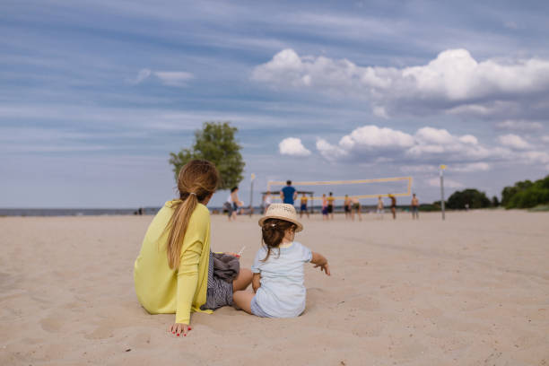 istock Mother and daughter watching a volleyball game on a beach 1009031930