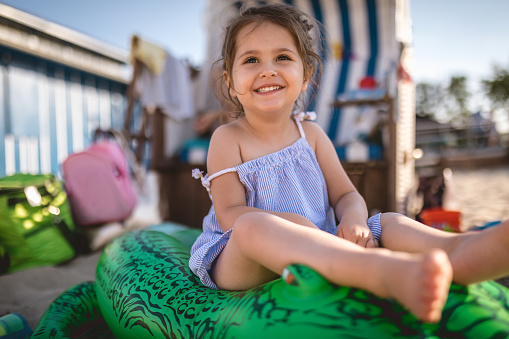 Lovely and cute child in a dress, enjoying a sunny day on a beach.
