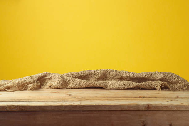 istock Empty wooden table with sackcloth over yellow wall  background 1009036530