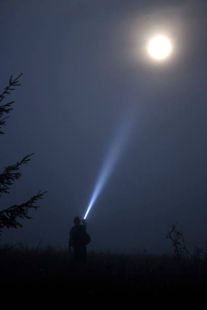 istock Man shines a flashlight in the night moon sky 1009055876