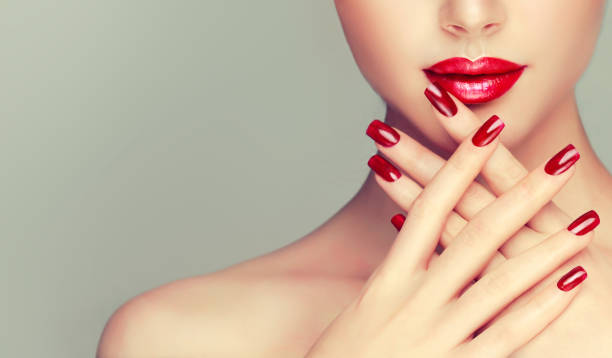 Stylish manicure and make up in the bright red colour. Part of human face. Perfect woman lips with ideal shape and colored by bright red lipstick and red manicure on the nails.Stylish evening image for young women. Fashion makeup and cosmetic. fingernail stock pictures, royalty-free photos & images