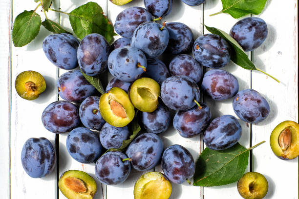 синие сливы на светлом деревянном фоне.fruits.the вид сверху - plum стоковые фото и изображения