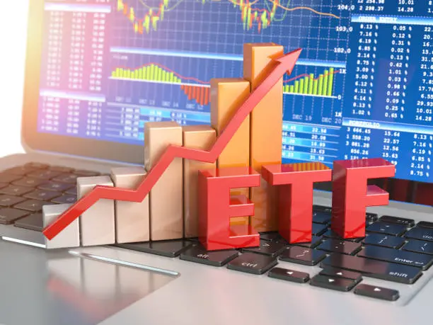 Photo of ETF exchange traded funds concept. Graph with ETF on the laptop keyboard with trade workstation app on the screen.