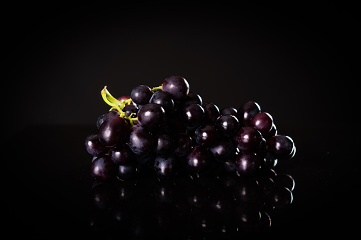 Purple grape over black background