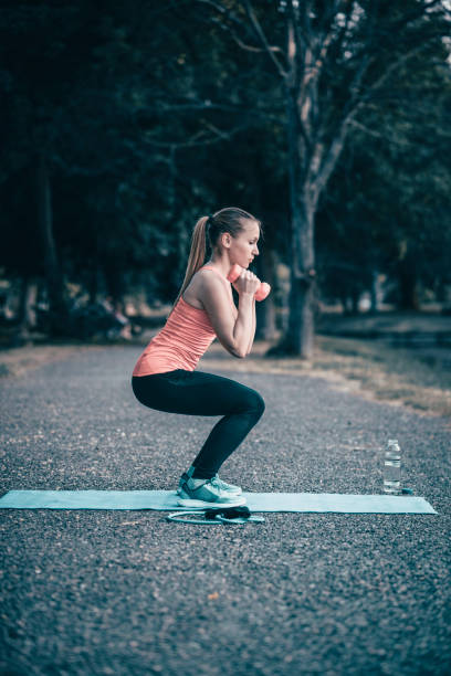 istock Fit Girl Doing Squats With Dumbbells In Public Park 1009145082