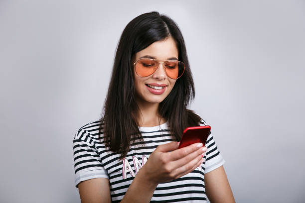 istock Young beautiful happy woman using smart phone. Isolated on grey background 1009147260