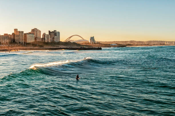surfers enjoying the waves during sunset - rsa imagens e fotografias de stock