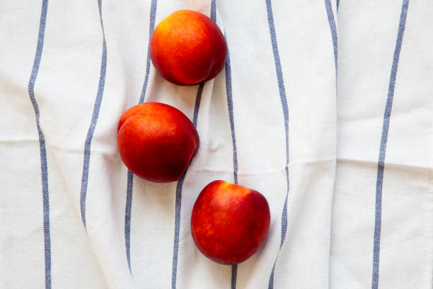 istock Nectarines on a striped napkin, top view. 1009183972
