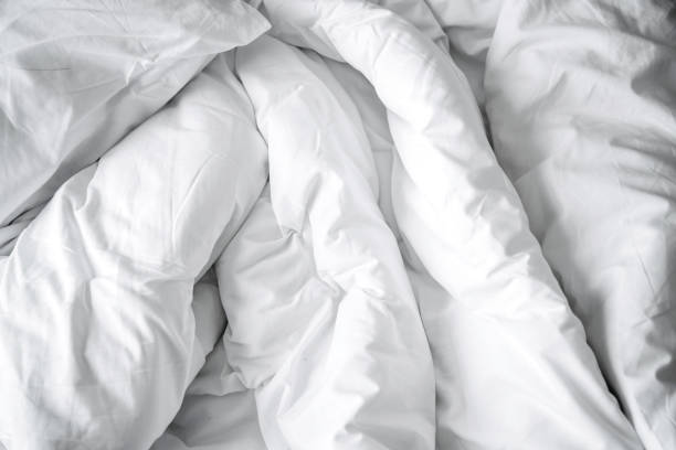 istock Unattended white cozy bed with white soft big pillow bedroom background. 1009216130