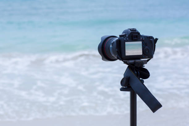 istock Dslr digital professional camera stand on tripod photographing Ocean, Blue sky and cloud landscape. 1009236064
