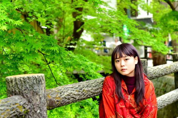 Young Japanese Woman Surrounded by Fresh Green Maple Foliage