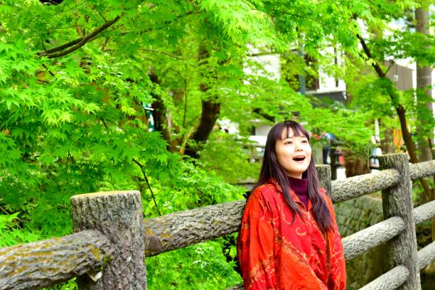 istock Young Japanese Woman Surrounded by Fresh Green Maple Foliage 1009286448