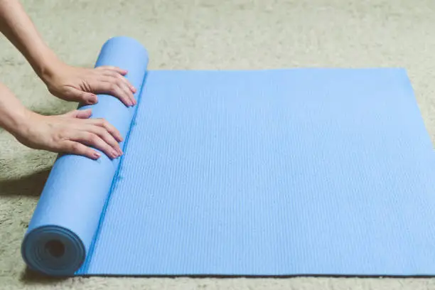 Caucasian woman in black clothes rolling blue yogamat