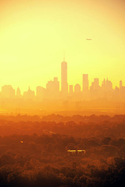 New York City downtown sunrise silhouette with airplane viewed from park