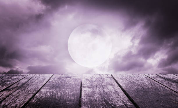istock Halloween background. Spooky sky with full moon and wooden table 1009330492