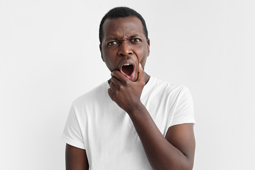 Young african american man isolated on grey background, with eyes wide open with fear or amazement, covering open mouth with palm, astounded with news