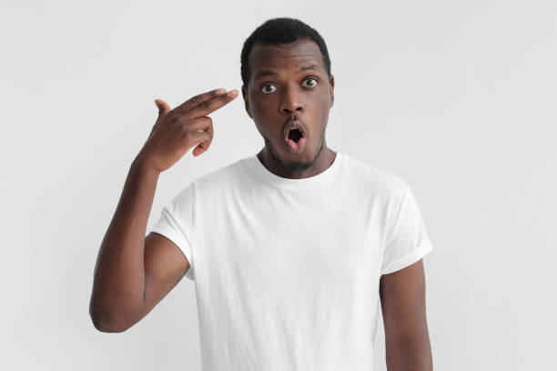 istock Young african american man committing suicide with finger gun gesture, shooting himself making finger pistol sign, isolated on grey background 1009362296