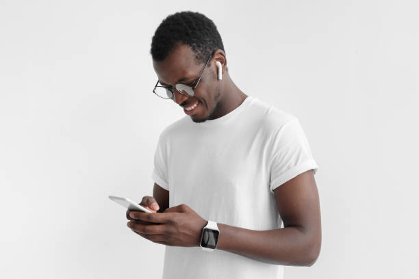 istock Young attractive african american dark skin man looking and at smartphone with  while texting, using mobile phone, isolated on gray background 1009362330