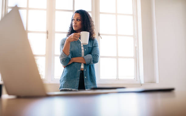 istock Businesswoman standing in office drinking coffee 1009369404