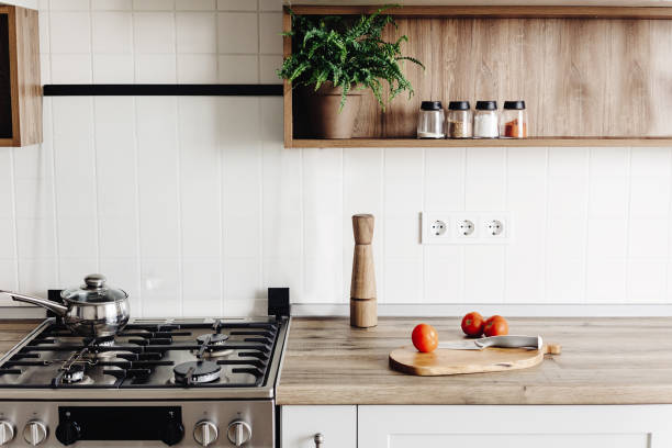 istock Cooking on Modern Kitchen  in scandinavian style. stylish grey kitchen interior design with modern furniture and stainless steel appliances. wooden countertop, steel stove, board,knife and spices 1009379478