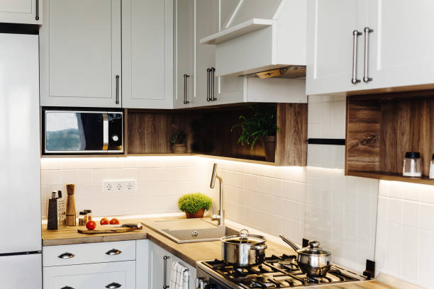 istock Modern Kitchen design in scandinavian style. stylish light grey kitchen interior with modern furniture and stainless steel appliances. wooden countertop, steel stove, board,knife and spices 1009379598