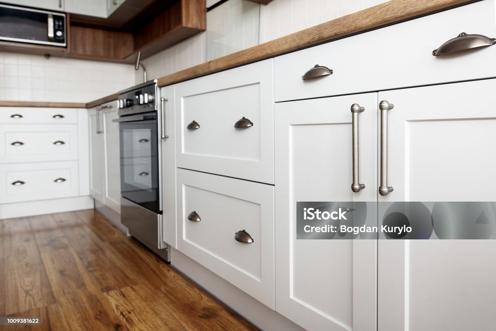 Stylish light gray handles on cabinets close-up, kitchen interior with modern furniture and stainless steel appliances. kitchen design in scandinavian style Cabinet Stock Photo