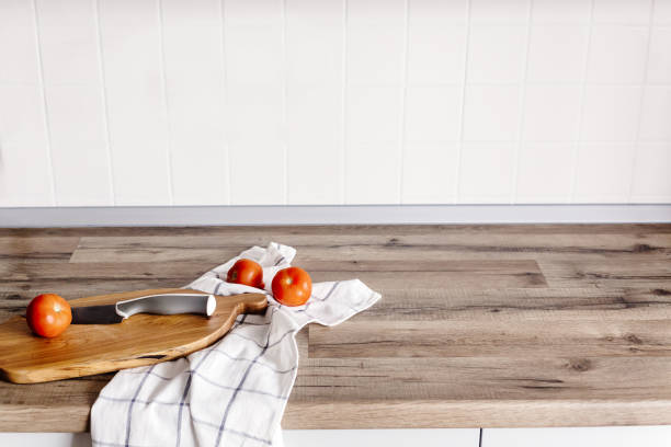 istock wooden board with knife, tomatoes, towel on modern kitchen countertop. simpli image, cooking concept. cooking food. Stylish kitchen interior design in scandinavian style 1009383826